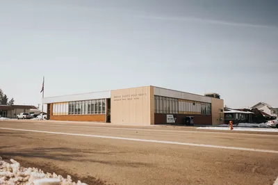 A tranquil view of a United States Post Office during winter with snow, clear sky, and urban surroundings.
